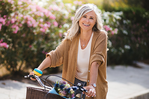 A woman smiling on a bike. Links to Gifts of Appreciated Securities